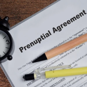 Prenuptial agreement document with pen and clock on desk